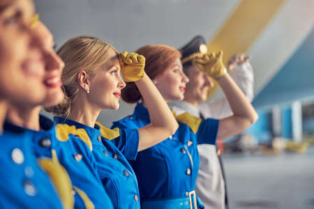Blonde Caucasian woman air hostess in leather gloves in front of passenger airplaneの写真素材