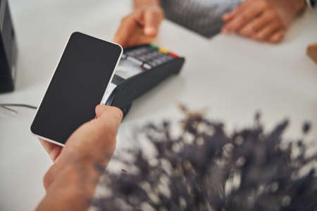 Customer paying for a purchase with a help of phoneの写真素材