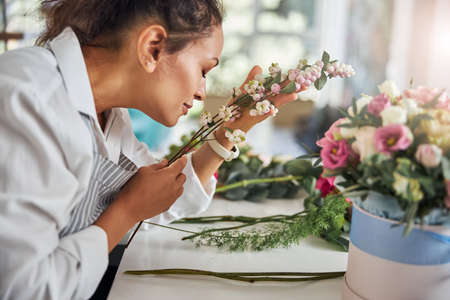 Professional flower shop worker enjoying the aroma of white berries
