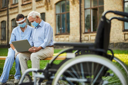 Two people looking at the screen of computer outdoorsの写真素材