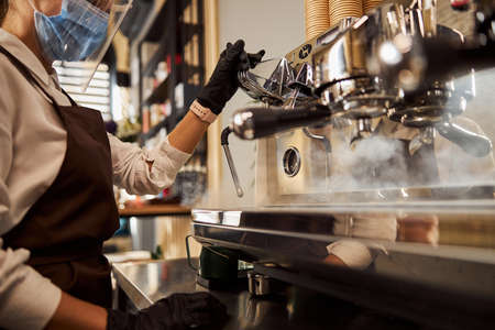 Woman waiter cleaning coffee machine in the cafe barの写真素材