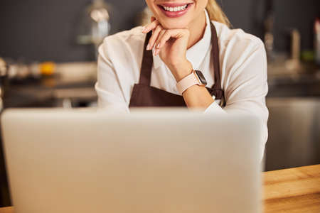 Happy cheerful young woman standing in the indoors at the laptop
