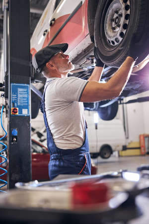 Auto mechanic repairing car wheel at service station