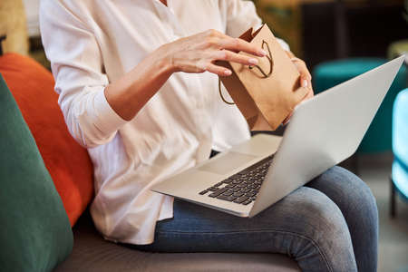 Business lady with grey laptop with gift in handsの写真素材