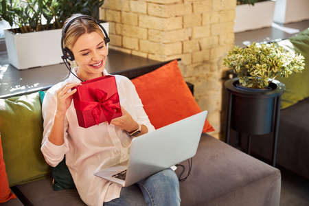 Beautiful lady in headphones having conversation on laptop while surfing internetの写真素材