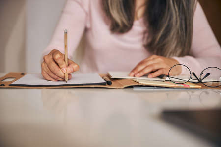 Woman sitting at the table and filling out documentsの写真素材