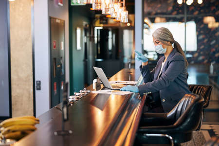Businesswoman in medical mask using laptop at business center