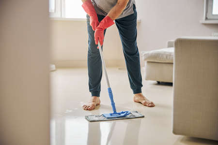 Dutiful man cleaning his appartment with a mopの写真素材