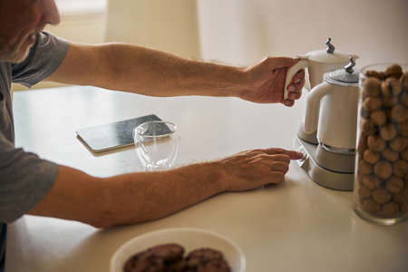Aged man turning on his kettle to make some teaの写真素材