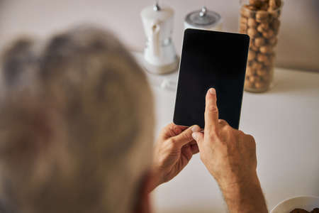 Tech-smart man holding a portable tablet in kitchenの写真素材