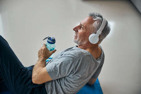 Active senior man in headphones smiling while resting from exercisingの写真素材