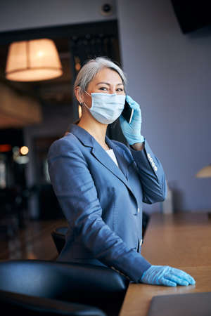 Charming woman in medical mask talking on mobile phoneの写真素材