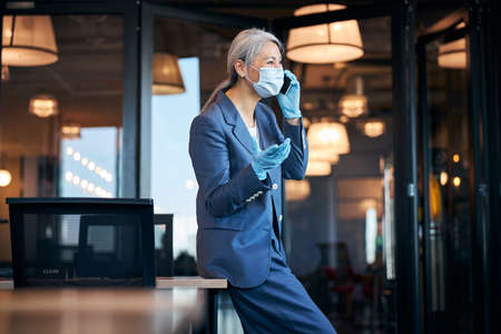 Businesswoman in protective face mask talking on cellphoneの写真素材