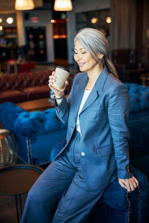 Beautiful joyful woman drinking coffee in cafeの写真素材