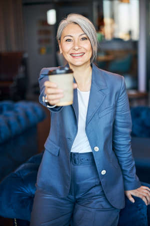 Cheerful woman offering takeaway cup of coffee