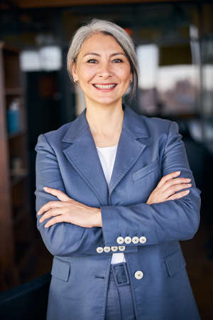 Joyful woman with crossed arms standing in office