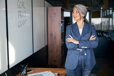 Cheerful businesswoman standing by whiteboard in officeの写真素材