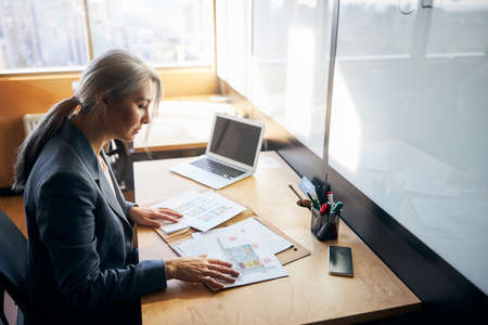 Beautiful businesswoman sitting at the table with laptop and papers