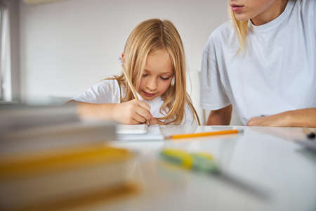 Cute small miss doing home work with nanny in home at the weekend