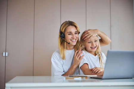 Beautiful little girl having fun with cheerful female in home at the weekendの写真素材