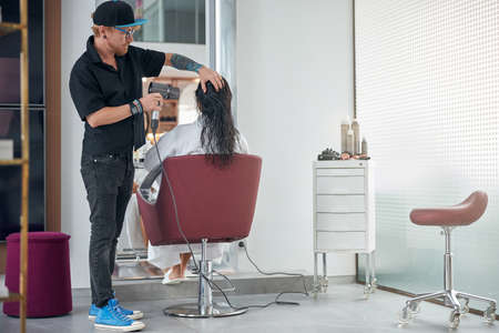 Stylist pointing the hair dryer at the wet hair