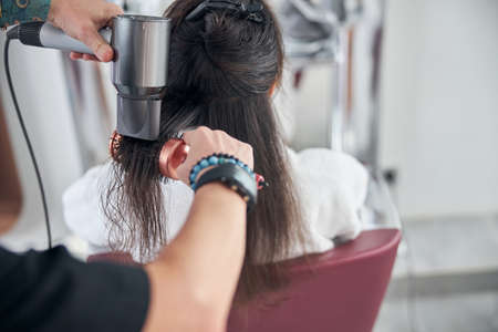 Manipulations with the woman hair sitting back to the viewerの写真素材