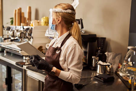 Waitress in the cafe with modern gadget looking awayの写真素材