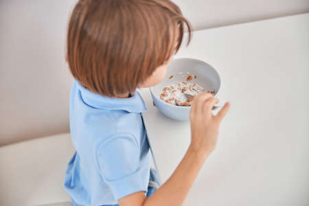 Cute child eating cereal at the kitchen table