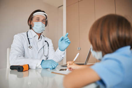 Experienced medic receiveing a child patient at the officeの写真素材