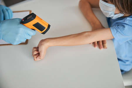 Adorable little boy having his temperature measured with contactless thermometerの写真素材