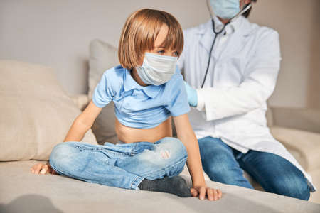 Cute kid sitting nicely while being examined by medical workerの写真素材