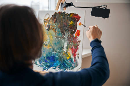 Focused artist with palette-knife painting on canvasの写真素材