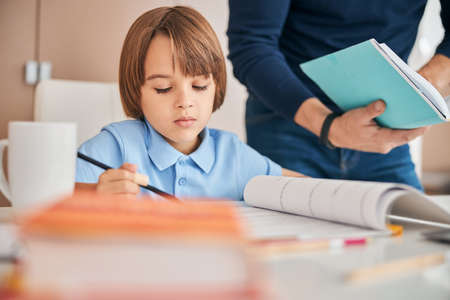 Child doing homework and his parent checking it