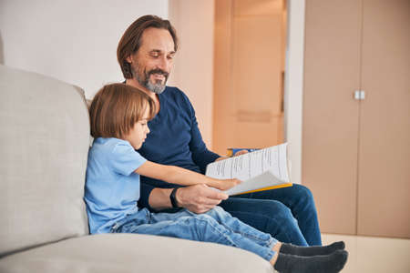 Happy parent reading to his child at home