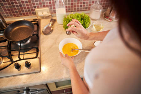 Woman is spicing the omelet with salt