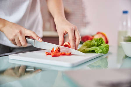 Knife cutting through a pepper on a board