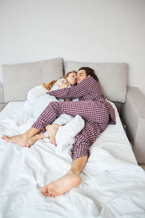 Beautiful young couple sleeping and cuddling at homeの写真素材