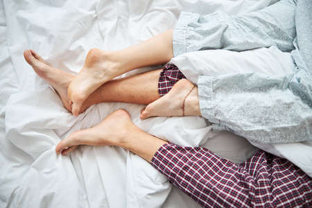 Loving couple with intertwined legs resting in bed