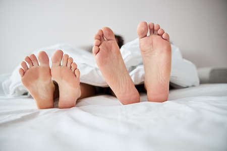 Young couple with bare feet resting in bed