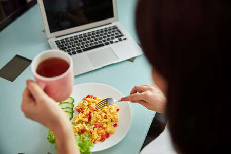 Female with a fork eating her breakfastの写真素材