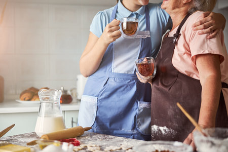 Two bakers having tea and hugging near kitchen tableの写真素材