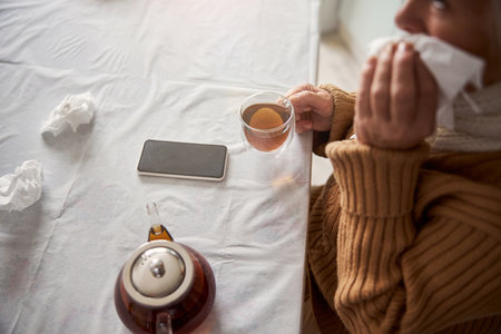 Old woman sitting at the table with cup of teaの写真素材