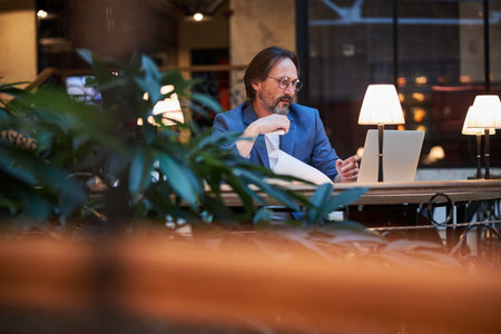 Concentrated bearded gentleman working on his laptopの写真素材