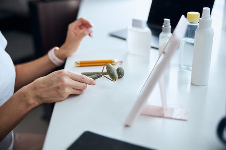 Beautiful female hand with roller massager above the table in bedroomの写真素材