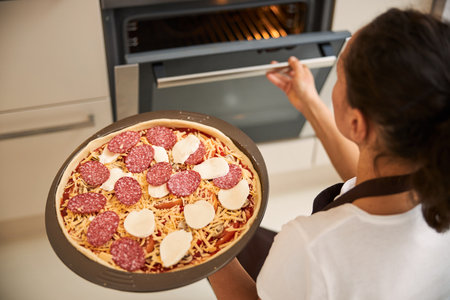 Woman opening the oven before baking pizzaの写真素材