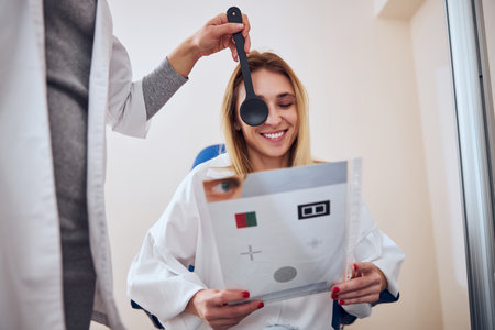 Beautiful elegant female having pleasantly talking with doctor at the examining vision in optometrist cabinetの写真素材