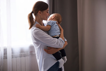 Positive delighted young parent lulling her babyの写真素材