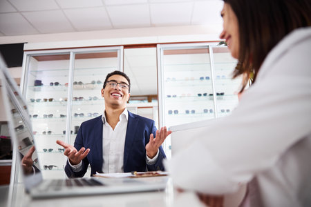 Male client talking to a woman opticianの写真素材