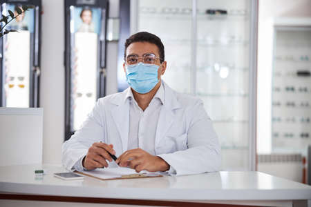 Bespectacled young optician seated in his office