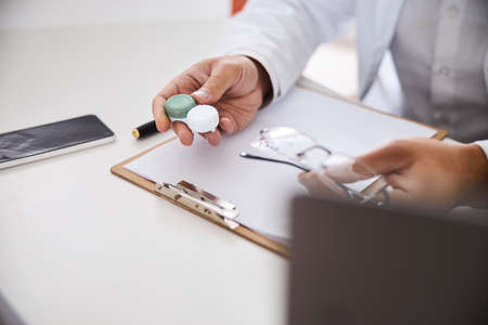Male optician with contacts and spectacles sitting at the desk
